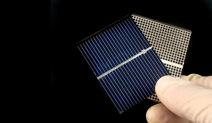 A person holding a solar cell in their hand.